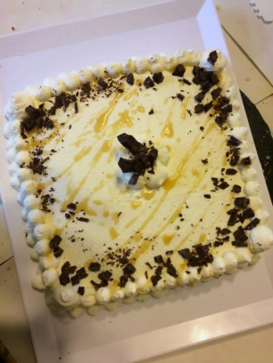 Gâteau carré à la crème vanille parsemé d'éclats de chocolat et de caramel